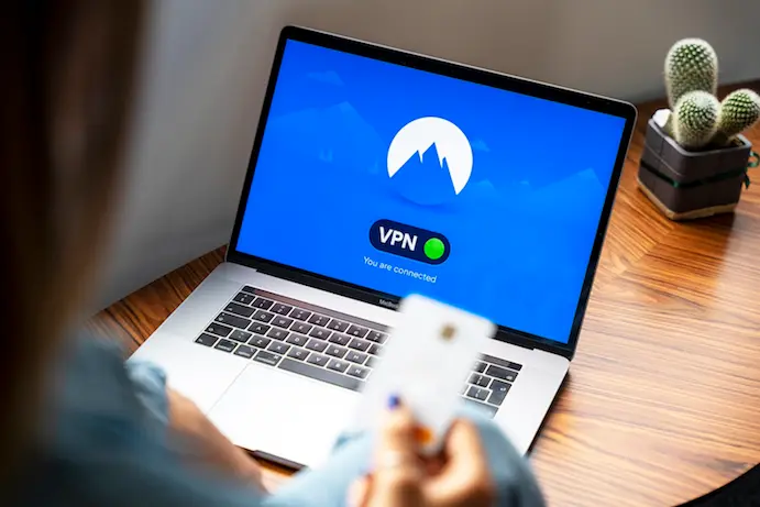 なぜ今VPNが必要なのか？のアイキャッチ画像 VPNが表示されたラップトップとクレジットカードを手にした女性