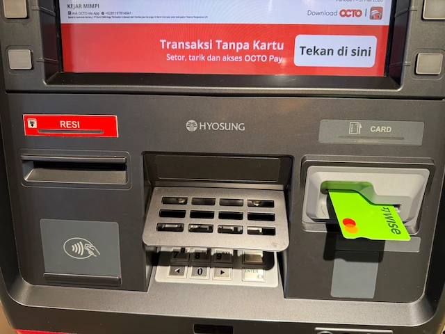 バリ島のCIMB Niaga ATMにWiseカードを挿入している様子。カード挿入口の横にOCTOアプリの案内が表示されている